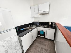 a small kitchen with white cabinets and a sink at Aloha Imsouane in Imsouane