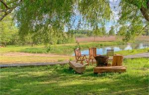 Awesome Home In Vrena With Wifi في Vrena: كرسيين ومرجيح في العشب بجانب البحيرة