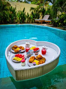 een dienblad met eten op een tafel naast een zwembad bij Senang Private Villa in Gili Trawangan