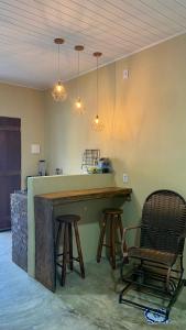 a kitchen with a bar with two chairs and lights at Milagres Retrô- Studio in São Miguel dos Milagres