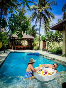 a man and a woman sitting in a swimming pool at Senang Private Villa in Gili Trawangan