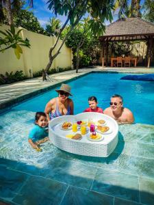 a family in a swimming pool with a table in the water at Senang Private Villa in Gili Trawangan