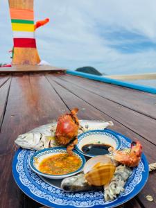 a plate of food with seafood on a wooden table at เกาะลิบงซันไรส์ โฮมสเตย์ Koh libong sunrise Homestay in Ko Libong