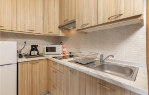 eine Küche mit Holzschränken, einer Spüle und einer Mikrowelle in der Unterkunft Cozy Apartment In Crikvenica With Kitchen in Crikvenica