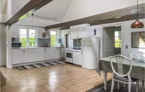 a kitchen with white cabinets and a table and a table and chairs at 2 Bedroom Gorgeous Home In Allinge in Allinge