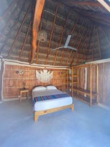 a bedroom with a bed in a straw roof at Cabañas Cinco Elementos in Celestún