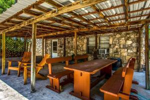 3H Ranch Mountain Retreat في Medina: فناء به طاولات وكراسي خشبية وجدار حجري