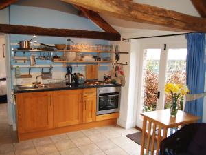 a kitchen with wooden cabinets and a sink and a table at Sycamore Cottage in Ellonby
