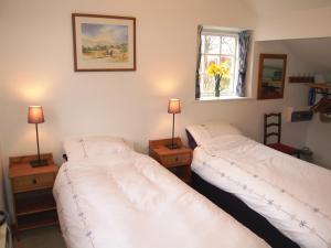 two beds in a room with two lamps and a window at Sycamore Cottage in Ellonby