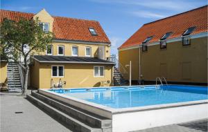 a swimming pool in front of two buildings at Amazing Apartment In Gudhjem With 2 Bedrooms, Wifi And Outdoor Swimming Pool in Gudhjem
