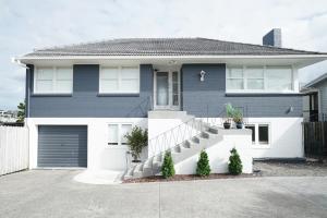 uma casa azul e branca com uma entrada em Bright & Central Home em Auckland