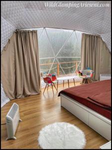 a bedroom with a tent with a bed and chairs at WildGlampingArieseni in Arieşeni