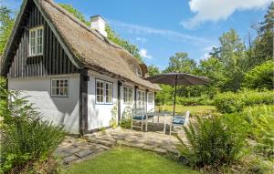 um chalé com um guarda-sol, uma mesa e cadeiras em 2 Bedroom Cozy Home In Gudhjem em Gudhjem