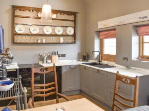 a kitchen with a sink and a counter with chairs at The Hen House in Bodiam