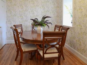 Mercy Cottage - Beaufort Estate في Belladrum: طاولة طعام مع كراسي و مزهرية مع نبات