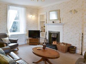 Mercy Cottage - Beaufort Estate في Belladrum: غرفة معيشة بها موقد وأريكة وطاولة