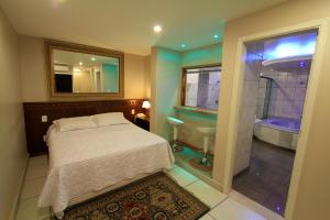 ein Schlafzimmer mit einem Bett und ein Badezimmer mit einer Badewanne in der Unterkunft Vicenza Apart Hotel in São João del Rei