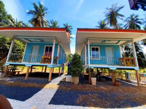 a blue house with two balconies and palm trees at Patcharin Homestay in Ban Lo Pla Lai (1)