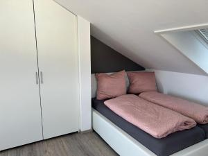 a room with a bed with pink pillows at Timeless - die Ferienwohnung in Wasserburg in Bettnau
