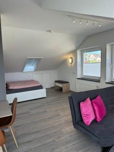 a room with a couch and a bed with pink pillows at Timeless - die Ferienwohnung in Wasserburg in Bettnau