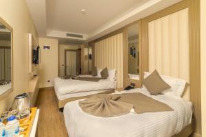 Habitación con 2 camas y mesa con botellas de agua. en Asilzade Hotel Sirkeci, en Estambul