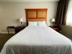 a large white bed in a room with two lamps at Anavada Inn & Suites - Prince George in Prince George