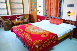 1 dormitorio con 1 cama con colcha roja y dorada en Kasera Paradise en Būndi