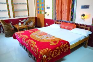 1 dormitorio con 1 cama con colcha roja y dorada en Kasera Paradise, en Bundi