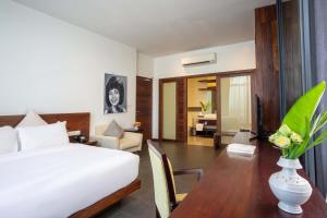 Maison Leab في سيام ريب: غرفة نوم مع سرير ومكتب مع إناء من الزهور