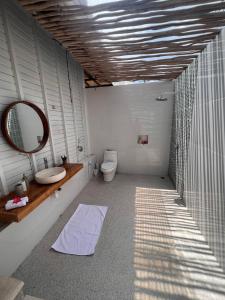 La salle de bains est pourvue d'un lavabo, d'un miroir et de toilettes. dans l'établissement The KUBU 221, à Nusa Lembongan