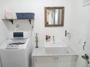 uma casa de banho branca com um lavatório e um espelho em Vacances a la mer Ishigaki em Ishigaki