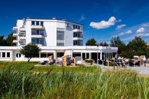 Ein weißes Gebäude mit Leuten, die draußen sitzen. in der Unterkunft Strandhotel Bene in Burgtiefe auf Fehmarn 