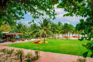 a park with a lawn with palm trees and a building at Thiên Tân Hotel in Con Dao