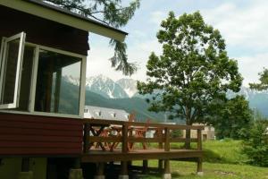 a house with a deck with mountains in the background at Hakuba Powder Lodge in Hakuba