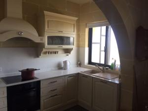 uma cozinha com armários brancos, um lavatório e uma janela em Entire apartment with Ramla Bay view (Gozo, Malta) em Il-Pergla