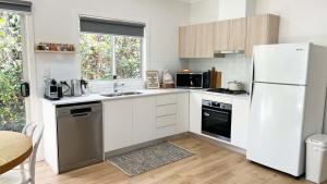 a kitchen with white cabinets and a white refrigerator at Honey Fig Cottage, Bowral in Bowral