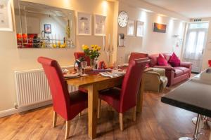 a dining room and living room with a wooden table and red chairs at The Old Bakery in Cromer