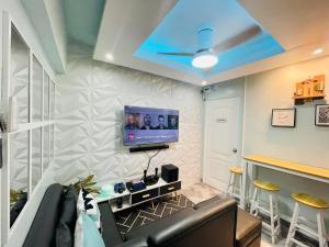 ein Wohnzimmer mit einem Sofa und einem Fernseher an der Wand in der Unterkunft The PAD Staycation 2BR Condo with PS4, Netflix, WIFI in Manila