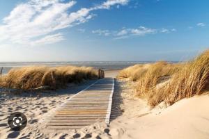een houten pad door het zand op een strand bij gîte neuf proche de la plage in Oye-Plage