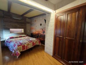 1 dormitorio con 1 cama y una pintura en la pared en Maison Manu, en Perosa Argentina