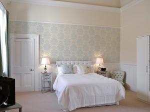 una camera con un letto bianco e due tavoli e due lampade di Lavender a Stokeinteignhead