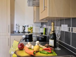 a kitchen with a bottle of wine and vegetables on a counter at Lavender in Stokeinteignhead
