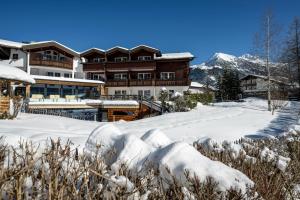 a lodge in the snow with mountains in the background at Naturhotel Lärchenhof in Mittelberg
