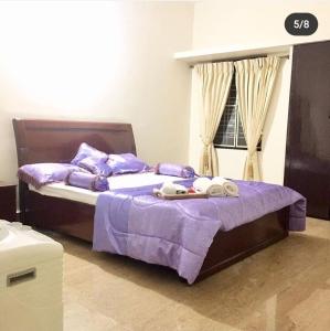 Somvārpet的住宿－Little bungalow Holiday Home, Coorg，一间卧室设有两张带紫色床单的床和窗户。