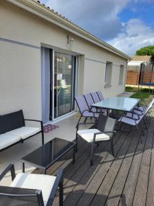 a deck with chairs and a glass table and chairs at Bienvenue à Bordeaux! Parking Pétanque Wi Fi in Beychac-et-Caillau
