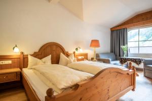 a bedroom with a large wooden bed and a chair at Naturhotel Lärchenhof in Mittelberg
