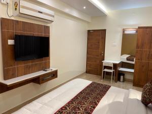 een hotelkamer met een bed en een flatscreen-tv bij Le Shiv Executive Suite in Theni