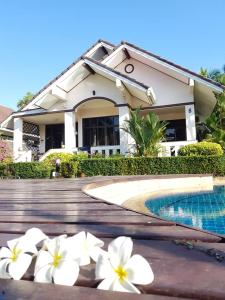 una casa con flores blancas frente a una piscina en House in Ban Phe, Thailand en Rayong