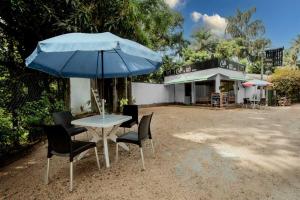 une table et des chaises avec un parapluie bleu dans l'établissement River Edge Eco Resort, à Kitulgala