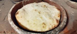 a pizza is being cooked in a pan at dimis ferdobi in Dimi